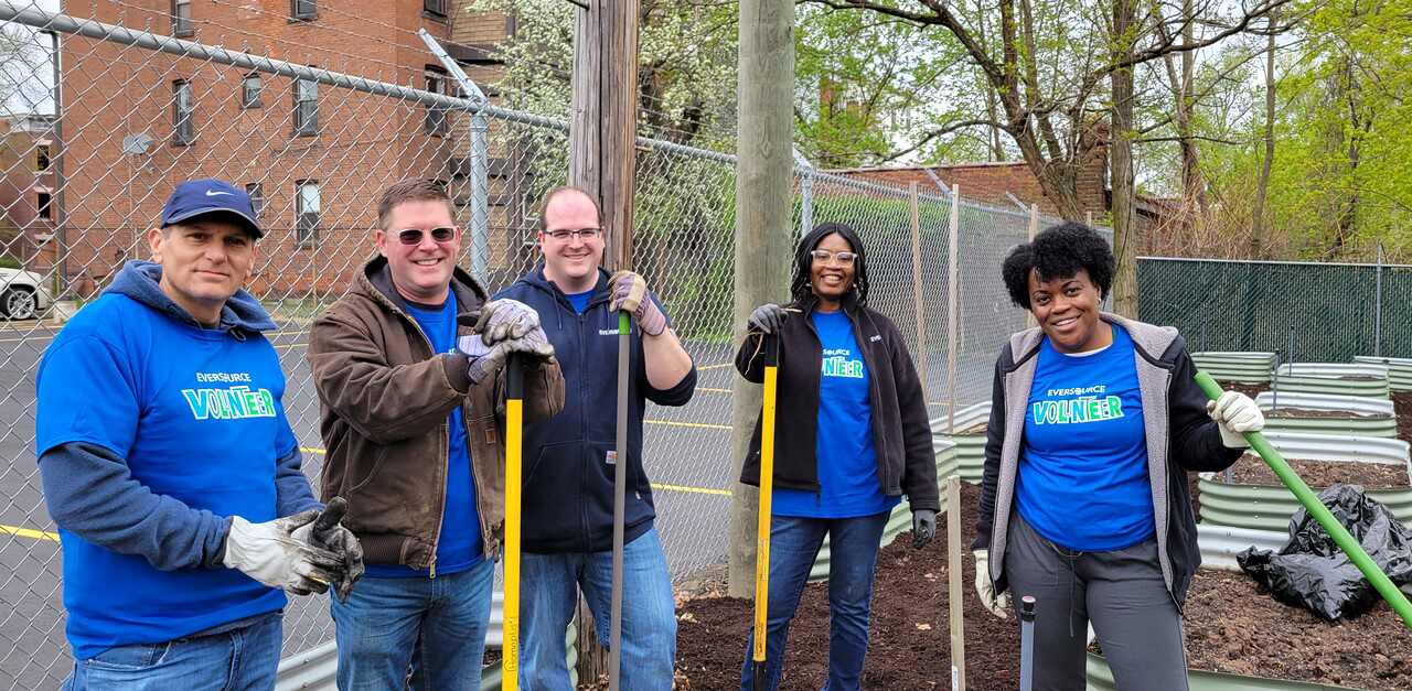 Employees posing with shovels during a volunteer cleanup event