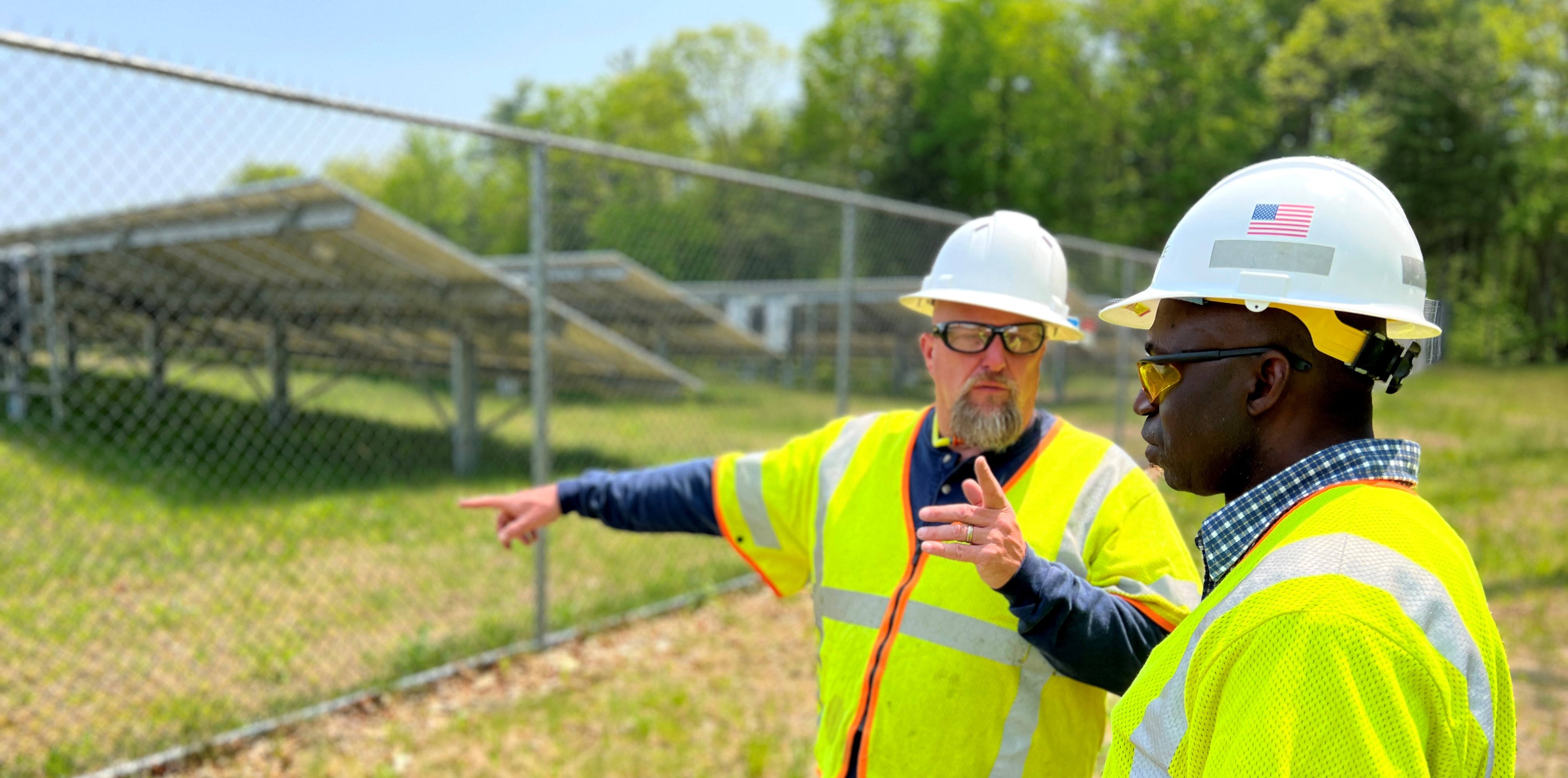 Employees in hard hats pointing to solar panels