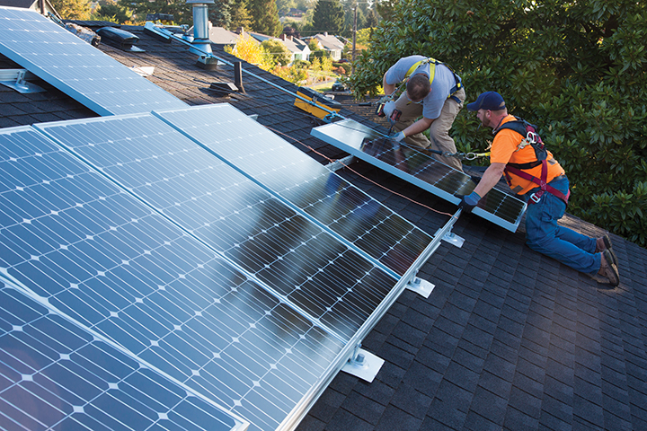 Workers install solar panels on a roof.