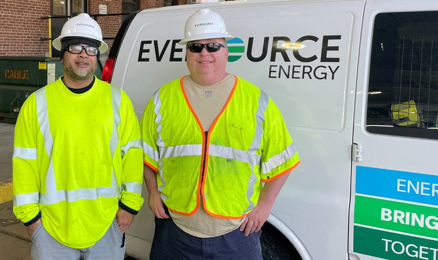 Vinny Foxx (left) and Sean Tierney pose in front of an Eversource van.