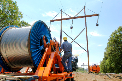 Eversource worker next to a spool of wire looking at a transmission pole