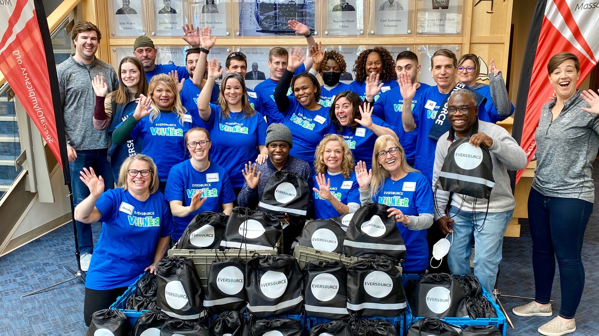 Volunteers wave while posing with donations. 
