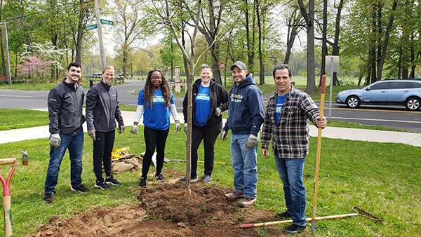 Employee volunteers planting a community garden and smiling with their shovels